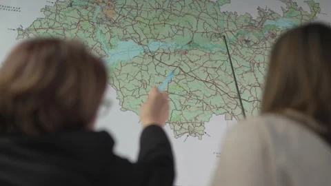 Woman uses pointer to highlight area on detailed paper map Stock Footage 327808297