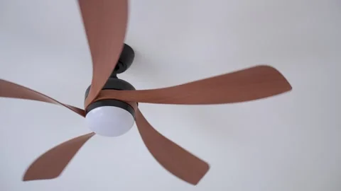 Woman uses remote control to operate ceiling fan mounted on ceiling Stock Footage 340336027