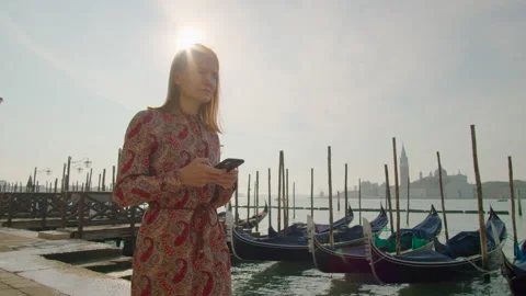 Woman Uses SmartPhone App Walking in Venice Canal with Gondolas in Summer Stock Footage