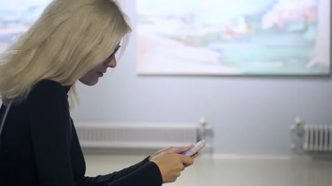 A woman uses a smartphone while sitting in a museum Stock Footage 163636446