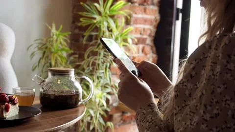 Woman uses smartphone while sitting in a pastry shop  Stock-Footage 200071474