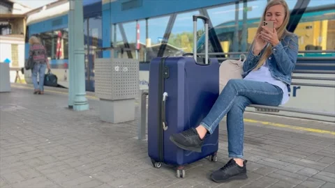 A woman uses a smartphone while waiting for a train at a railway station Video stock 253171704