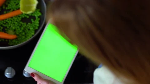 Woman uses a tablet computer in the kitchen and cooks. Top view. Green screen. Stock Footage 73722936