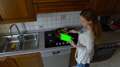 Woman uses a tablet computer in the kitchen and cooks . Top view. Green screen Stock Footage 73725323