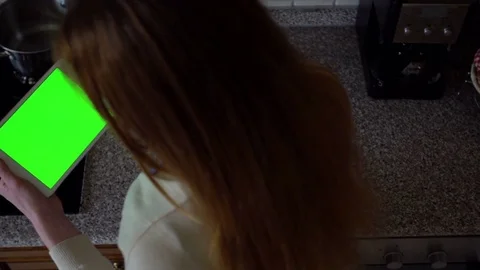 A woman uses a tablet computer in the kitchen. Top view. Green screen Stock Footage 73747648