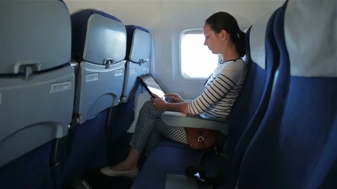 Woman uses tablet computer touchscreen in the plane Stock Footage 98121878