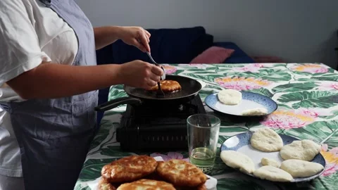 A woman uses two forks to remove fried meat patties from the pan. Stock-Footage 325310293