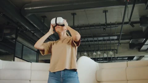 Woman uses virtual reality headset in modern office space during daytime and Stock Footage 330688913