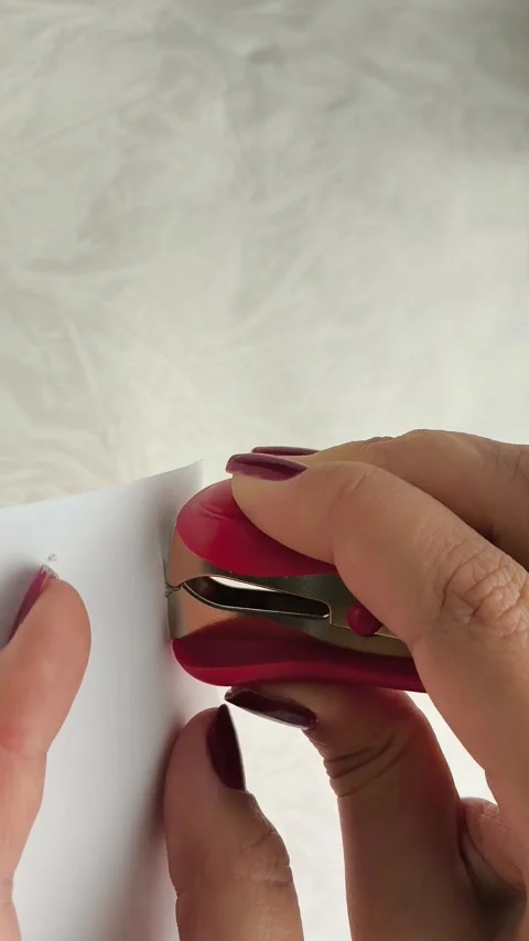 Woman using anti-stapler to remove metal staples from sheet of paper Stock Footage 318390585