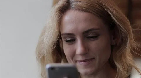 Woman using app on smartphone in cafe drinking coffee smiling and texting 스톡 동영상 68925622