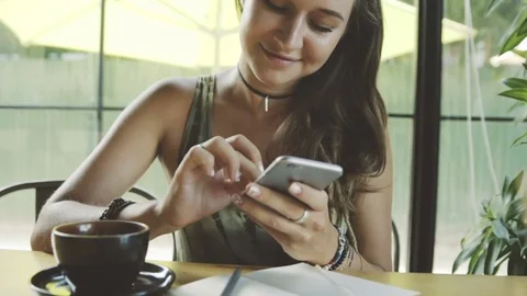 Woman using app on smartphone in cafe drinking coffee texting on mobile phone Stock Footage 73059148