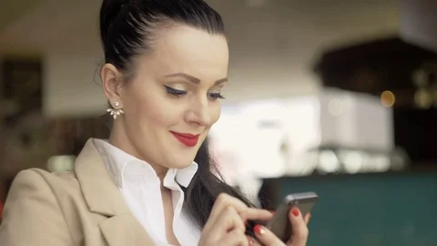 Woman using app on smartphone in cafe drinking coffee smiling and texting on Stockbeeldmateriaal 73417733
