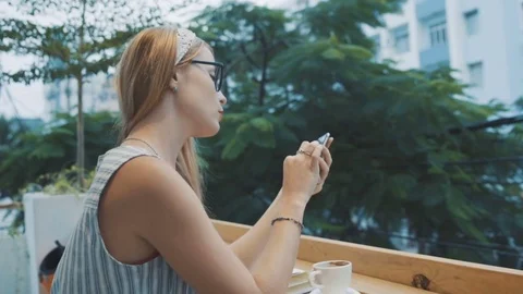 Woman using app on smartphone in cafe. Young girl taking off her glasses. Stock Footage 74368388