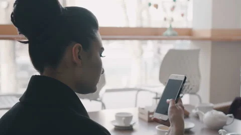 Woman using app on smartphone in cafe drinking coffee smiling and texting on Stock Footage 88688276
