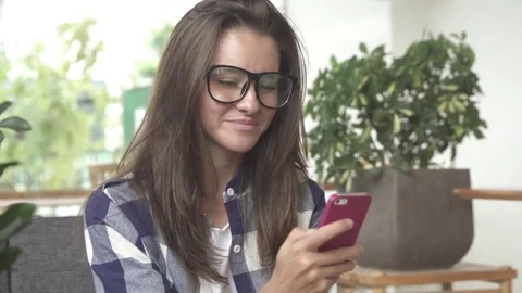 Woman using app on smartphone drinking coffee smiling, texting on mobile phone Stock Footage 77610533
