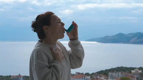 Woman using asthma inhaler during allergic attack outdoors Stock Footage 327187898