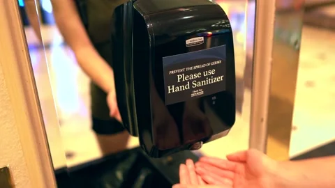 Woman using automatic commercial hand sanitizer machine Stock Footage 133465331