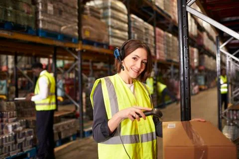 Woman using a barcode reader in a warehouse looks to camera Stock Photos