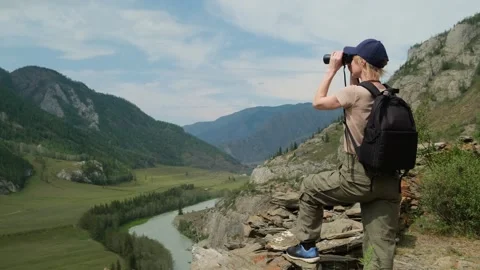 Woman using binoculars while hiking in mountains. Stock Footage 297753747