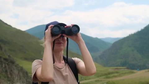 Woman using binoculars while hiking in mountains. Stock Footage 297754418