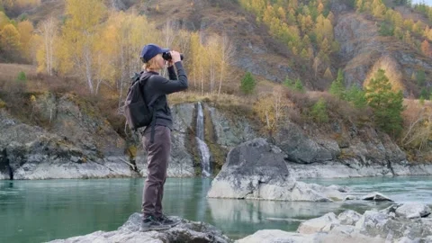 Woman using binoculars while hiking in mountains. Stock Footage 305730760