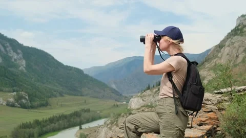 Woman using binoculars while hiking in mountains. Stock Footage 309616874
