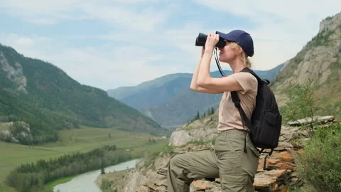 Woman using binoculars while hiking in mountains. Stock Footage 311692773