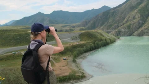 Woman using binoculars while hiking in mountains. Stock Footage 313430811