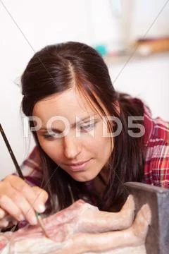 Woman using brush on statue in workshop Stock Photos