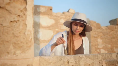 Woman in using brush while digging ancient temple Stock Footage 166569207