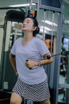 Woman using cable machine at gym Stock Photos