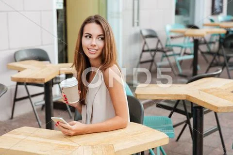 Woman using cell phone and drinking coffee in outdoor cafe Stock Photos