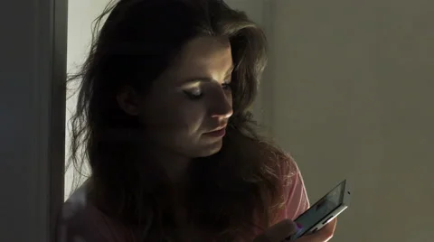 Woman using cellphone next to the window at night Видео 44100984
