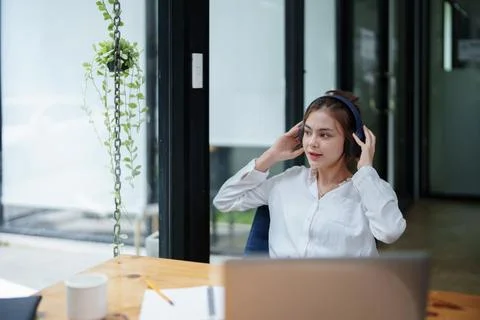 Woman using a computer and earphone during a video conference Stock Photos