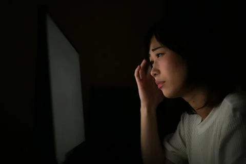 A woman using a computer in the dark Stock Photos