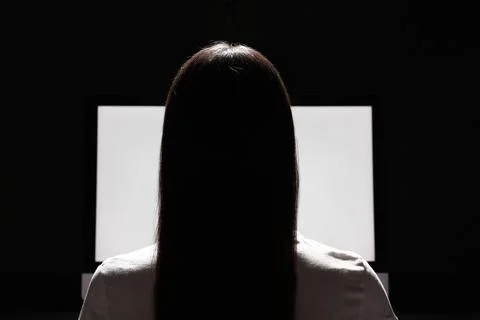 Woman using computer in dark room, back view. Internet addiction Stock Photos