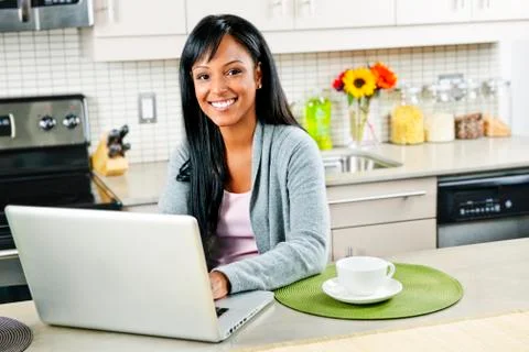 Woman using computer in kitchen Stock Photos