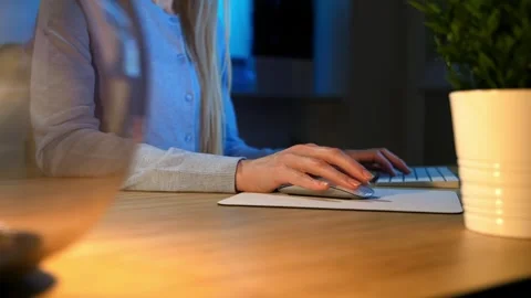 Woman using computer mouse and keyboard at wooden desk indoors nighttime Stock Footage 340138609