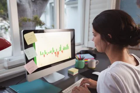 Woman using computer while sitting on her desk 스톡 사진