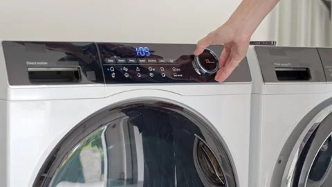 Woman using control panel to select wash cycle and settings on washing machine Stock Footage 344820241