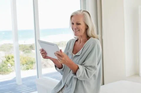 Woman using a digital tablet and smiling at home Stock Photos