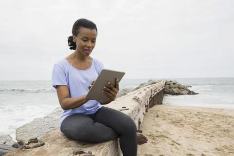 Woman using digital tablet on beach jetty Stock Photos