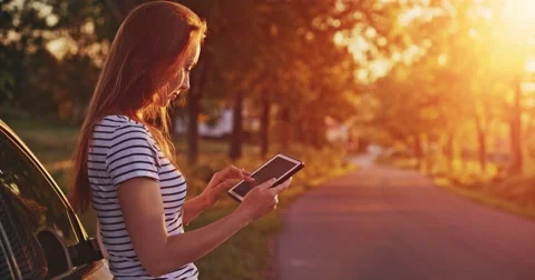 Woman using digital tablet by the car. Travel and technology. Slow motion. Vidéo 50955668