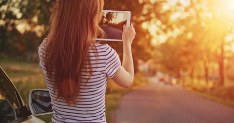 Woman using digital tablet by the car. Taking photos on a road trip outdoors. Vidéo 50956422