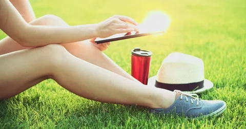 Woman using digital tablet computer sitting in the park, on a lawn. Slow motion Video stock 53104937