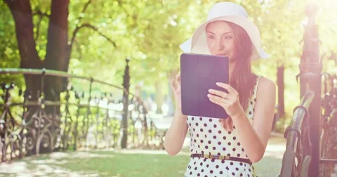 Woman using digital tablet in the green park outdoors. Beautiful young lady, Vidéo 52763834
