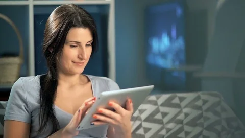 Woman using digital tablet at home sitting on sofa Video stock 75493718