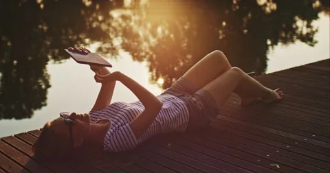 Woman using digital tablet outdoors, relaxing on a wooden jetty near the lake Video stock 51073134