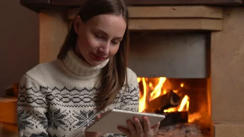 Woman using a digital tablet sits by the fireplace Stockbeeldmateriaal 147194670