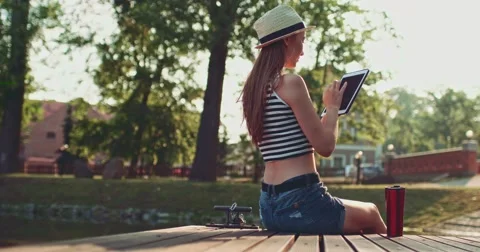 Woman using digital tablet sitting on a wooden jetty by the lake. Slow Motion. Vidéo 53110677